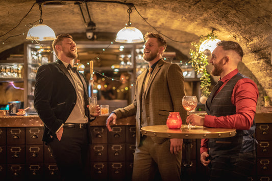 Friends enjoying some drinks at a Christmas party dressed in smart casual and formal menswear.