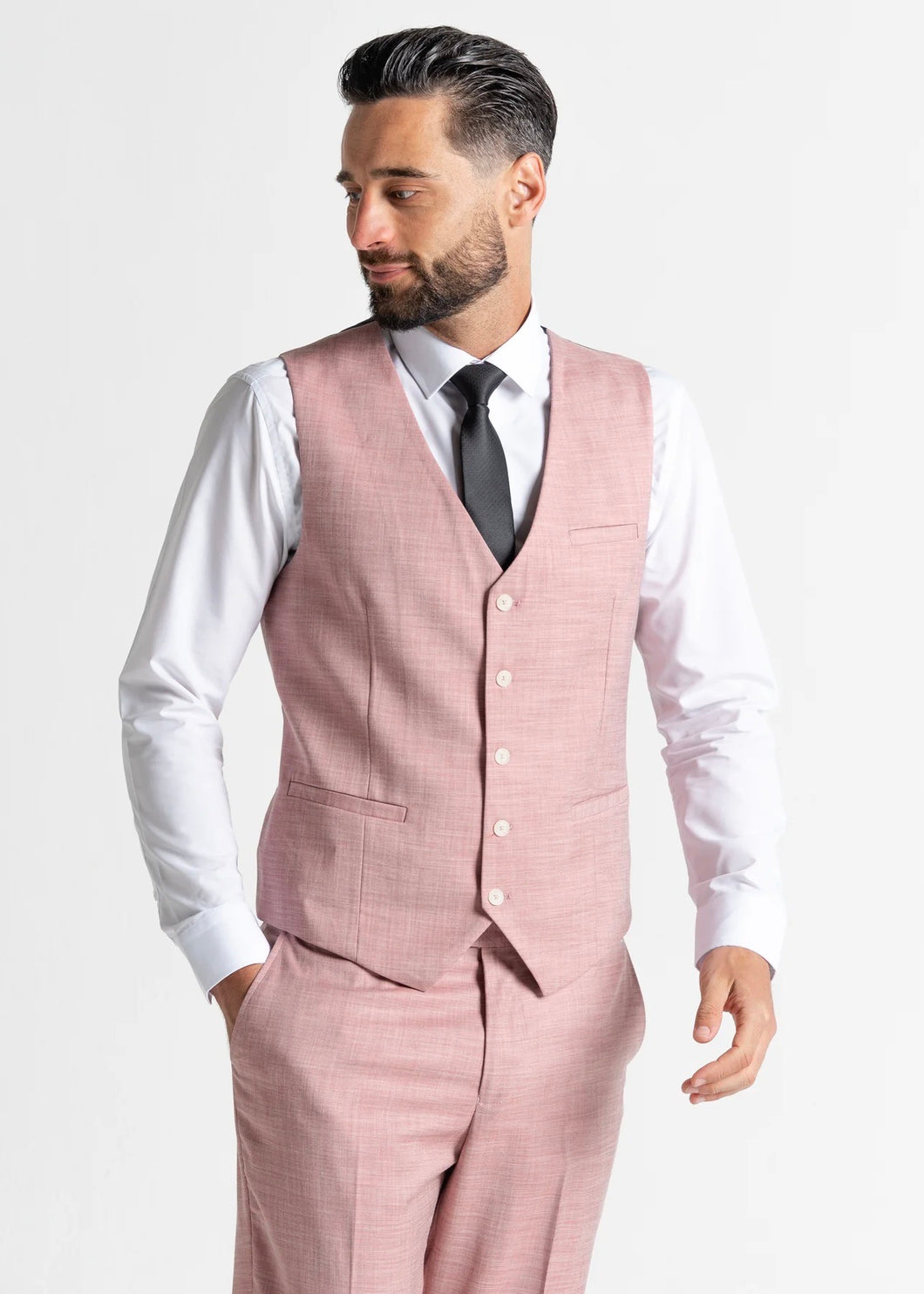 Model wearing the Edward Pastel Pink waistcoat and trousers looks away from the camera, showing off the side profile of the waistcoat and trousers.