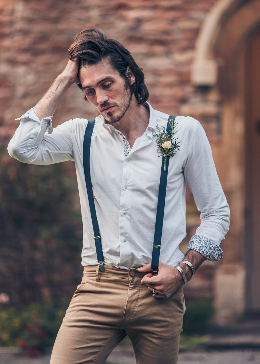 Boho groom looking disheveled, wearing SUAVE OWL White Shirt with chinos and braces.