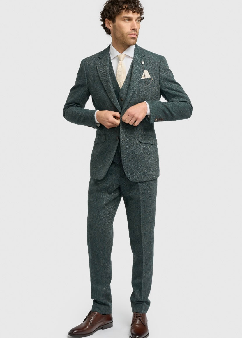 Man wearing a teal suit with a white shirt and brown shoes on a light grey background