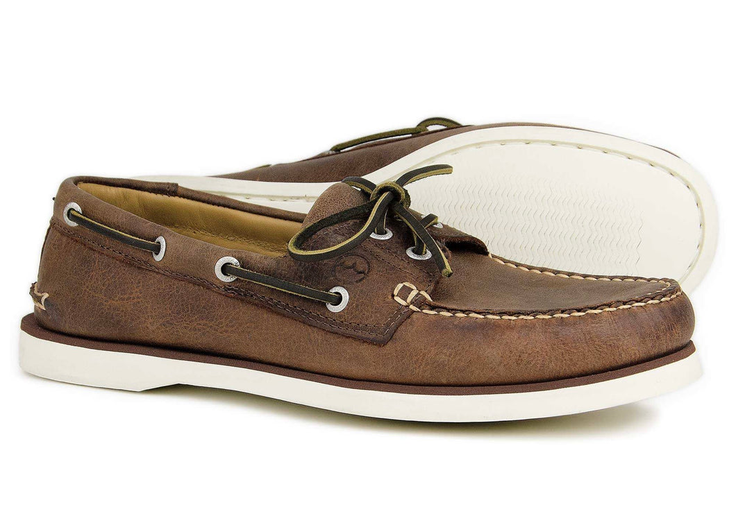 Tan brown boat shoes are shown up close, allowing for logo, stitching, and material details to be easily visible.
