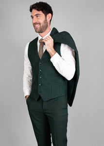 Model wears the Caridi Olive Waistcoat vest over a white shirt with Caridi Olive Trousers and a Caridi Olive jacket throw over his shoulder.
