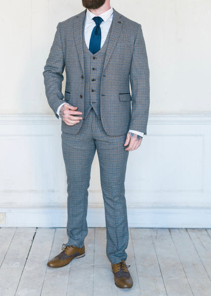 Marc Darcy Hardwick Checked Jacket modelled with a matching waistcoat and trousers. Styled with a white shirt and a blue silk tie to make it the perfect suit for a wedding or other formal occasion. Brown brogues also being worn by the model